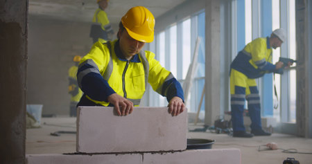 Construction worker using trowel and tools for building wall with bricks and mortarの写真素材
