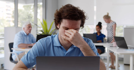 Young businessman get stress and headache when working with laptop on desk at modern officeの写真素材