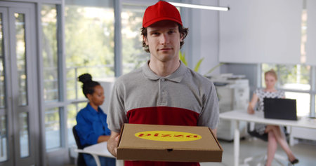Portrait of delivery guy in uniform holding pizza box