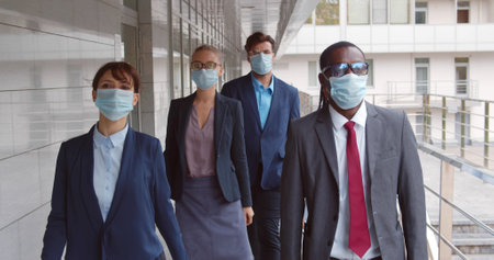 Business people in medical masks walking to office outdoors