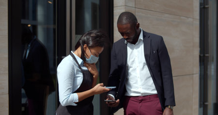 Restaurant worker screen vaccination qr-code on customer smartphone outside at entrance