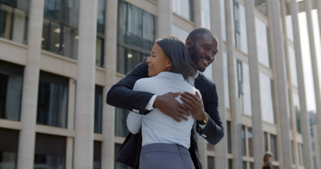 Low angle view of cheerful african colleagues triumphing and hugging on street.の写真素材