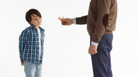 Cropped shot of man giving candy to preteen boy isolated on white backgroundの写真素材