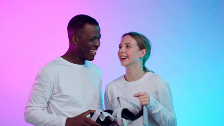 Happy African-American man and caucasian woman in white clothes remove vr goggles and laugh