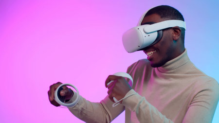 African-American man play video game in ve helmet and controllers isolated over neon backgroundの写真素材