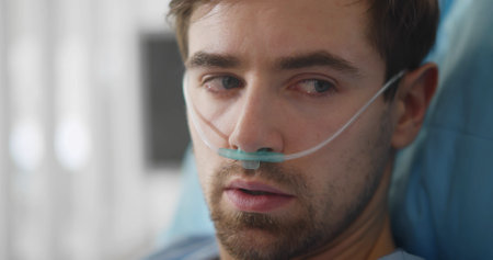 Upset man lying with oxygen nasal catheter on face preparing for surgeryの写真素材