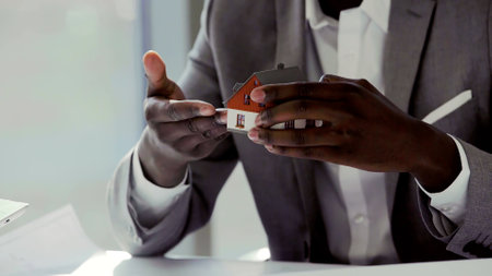 Cropped shot of african real estate agent holding mini-model of houseの写真素材