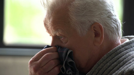 Portrait of senior man feeling sick with cold and fever at homeの写真素材