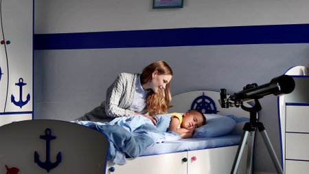 Young happy mother waking up son in morning