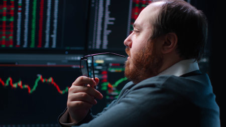 Close up of pensive fat trader look at multiple computer screens with dataの写真素材