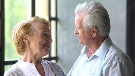 Romantic senior couple relaxing at home looking at each other and smilingの写真素材