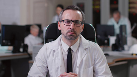 Portrait of serious doctor having online consultation sitting in officeの写真素材