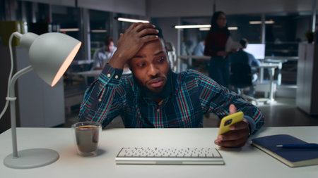 African-American businessman in office receive bad text on cellphone and feel stressedの写真素材
