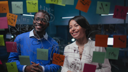 Happy African-American colleagues smile standing near glass boardの写真素材