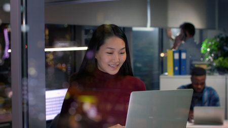 Asian woman work on laptop near window with night city center viewの写真素材