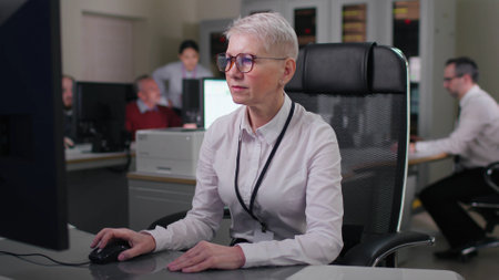 Mature businesswoman work on computer sitting at desk in officeの写真素材