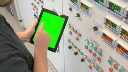 Engineer standing near control panel and holding digital tabletの写真素材