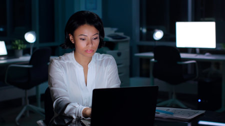 Exhausted African-American businesswoman working late in dark officeの写真素材