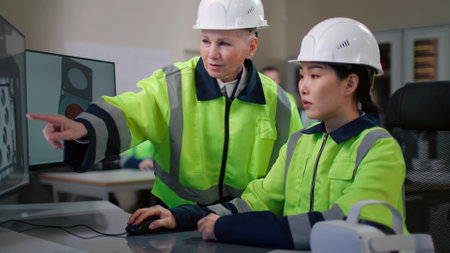 Portrait of project supervisor talking with a female industrial engineer point at computer screenの写真素材