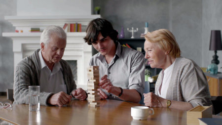 Happy grandparents and young grandson play board game at homeの写真素材