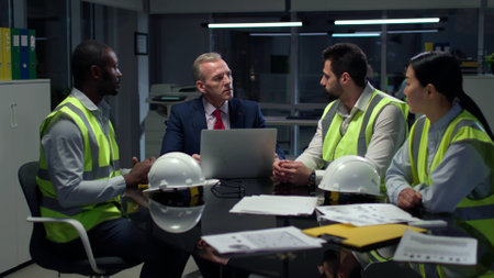 Mature businessman having meeting with industrial engineers late in officeの写真素材