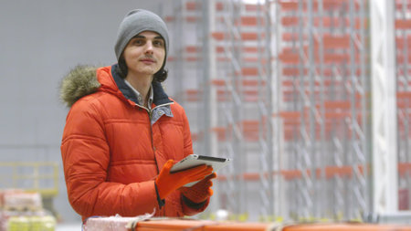 Portrait of young male engineer with digital tablet looking at camera inside new modern warehouse.の写真素材