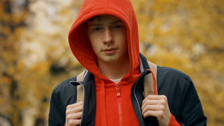 Sad caucasian teenager boy with backpck outdoors in autumn parkの写真素材