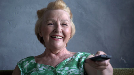 Close up of happy elderly woman watching TV and laughing