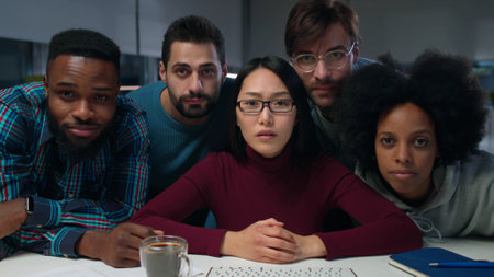 Surprised diverse business people looking at computer screen in dark officeの写真素材