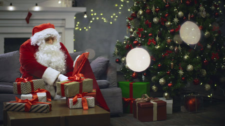 Santa Claus packing presents for Christmas holiday on background of New Year treeの写真素材