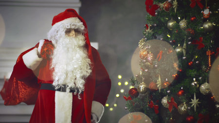 Santa Claus with present bag on background Christmas tree at New Year eveの写真素材