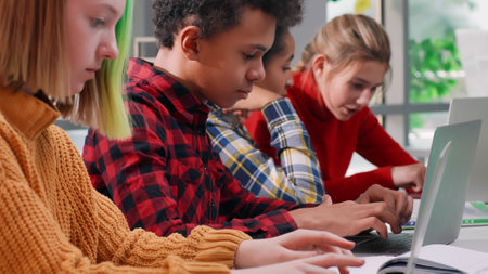 Close up of multiracial kids working on laptop at schoolの写真素材
