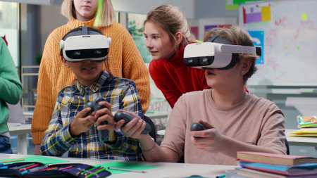 Teenagers looking at classmates in vr headset and joystick playing game in classroomの写真素材