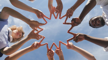 Bottom view of multiethnic teen students making finger circle outdoorsの写真素材