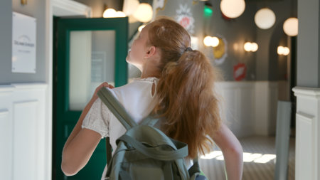 Back view of teen girl with backpack run in school corridor