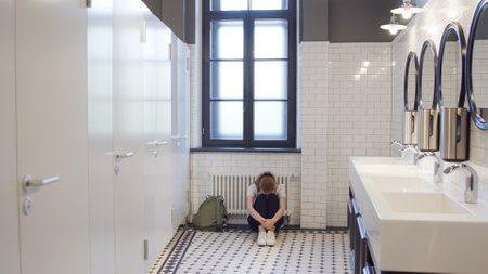 Sad and lonely teen girl sit on restroom floor aloneの写真素材