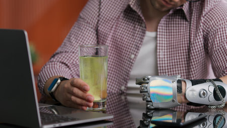 Cropped shot of man with artificial arm hold glass of waterの写真素材