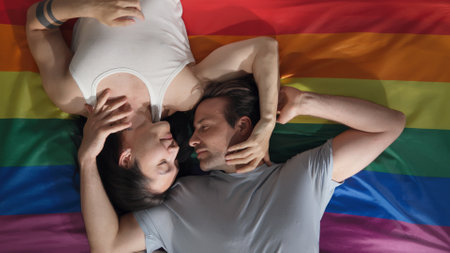 Top view of diverse young men lying on rainbow flag and cuddlingの写真素材