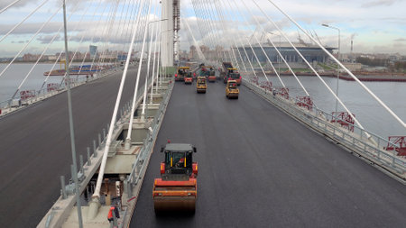 Above view of workers and machinery laying asphalt on highway bridgeの写真素材