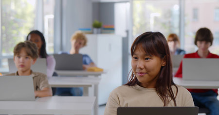 Diverse group of teen children using laptop sitting in classroom. Multiethnic teenage students...