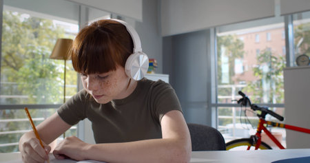 Teen pupil girl in white headphones talk with teacher during online lesson.の写真素材