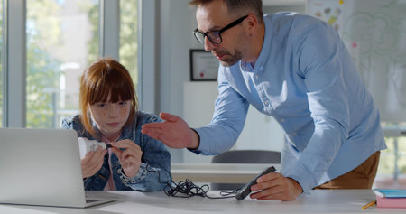 Mature teacher helping schoolgirl with engineering project at schoolの写真素材