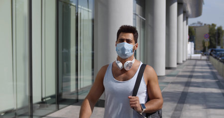 Young sporty man wearing face protective mask on city streetの写真素材