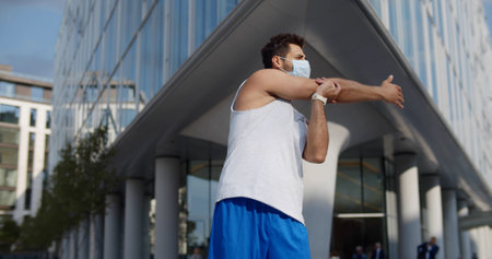 Young man in safety mask workout outdoors on city streetの写真素材
