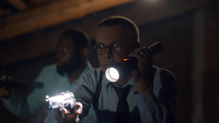Portrait of african and caucasian police officers catching criminal holding gun and flashlightの写真素材