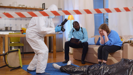 Forensic specialist taking photo of dead body while policeman interrogating witness sitting on couchの写真素材