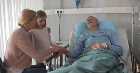 Upset grandmother and granddaughter visiting dying patient in hospital.の写真素材