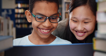 Close up of diverse school students studying and reading together in library.の写真素材