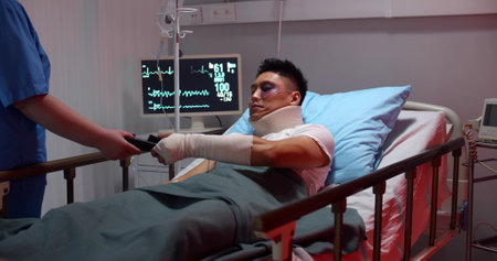 Injured male patient lying in hospital bed and paying with credit card for treatmentの写真素材