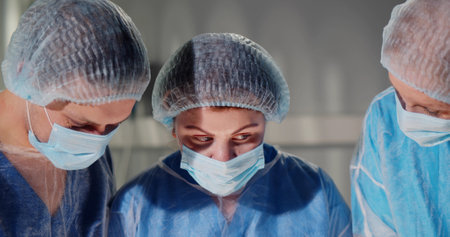 Concentrated professional surgical team operating patient in operating room at hospital.